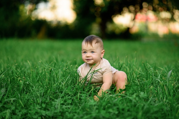 La niña de un año se sienta en la hierba.