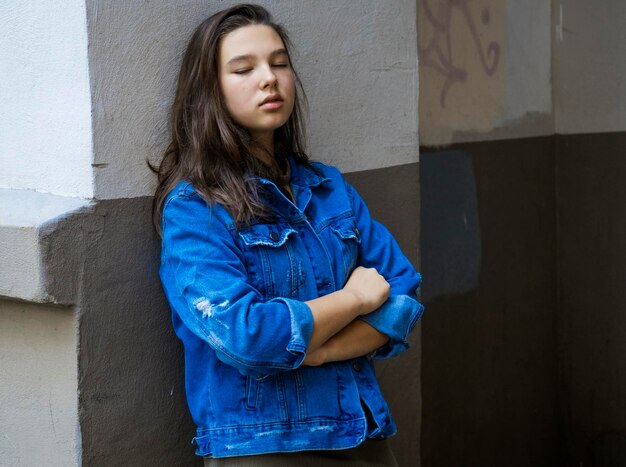 Foto niña apoyándose en la pared