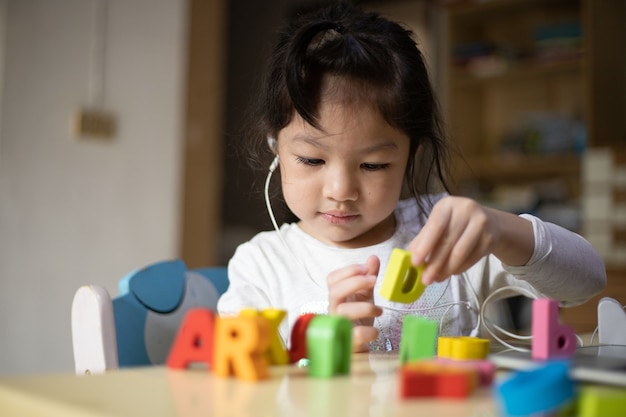 niña aprende en línea en casa con juguetes