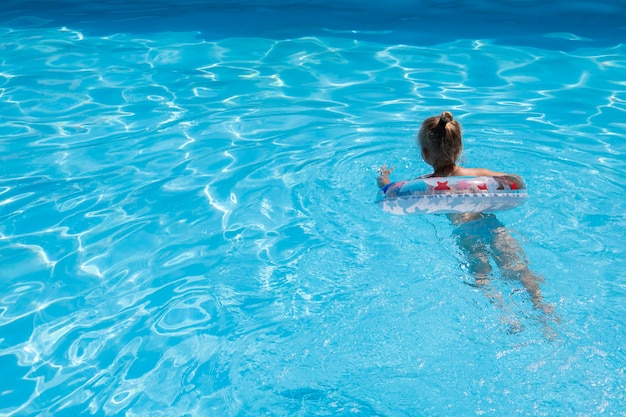 Niña aprende a nadar con un anillo inflable en la piscina