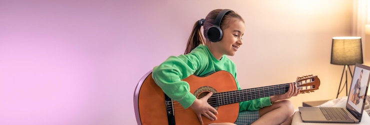 Foto la niña aprende a tocar la guitarra con la lección de música en línea