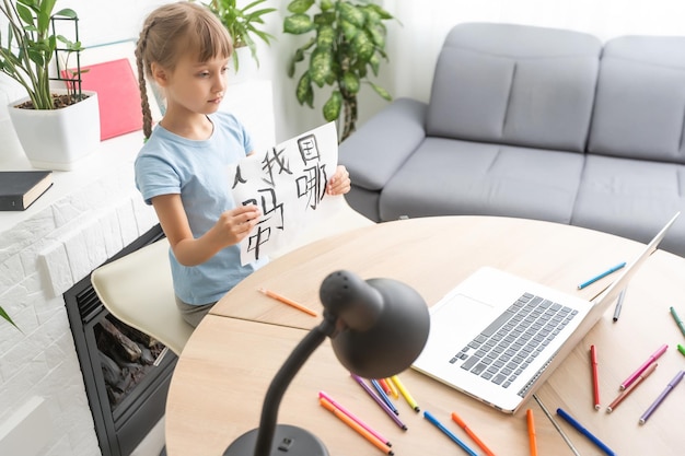 niña aprendiendo chino mientras usa su computadora portátil en la sala de estar en casa. concepto de actividad familiar.