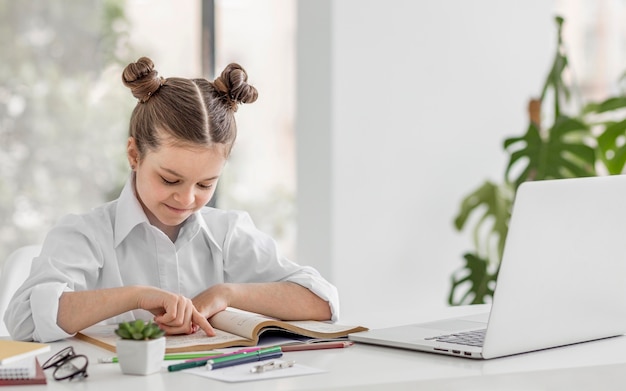 Foto niña aprendiendo de un libro para su próxima clase