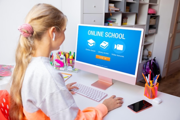 Niña aprendiendo en línea usando una computadora en casa
