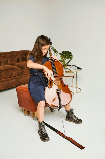 Niña aprendiendo a tocar el violonchelo en casa