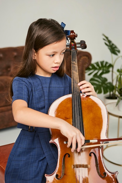 Foto niña aprendiendo a tocar el violonchelo en casa