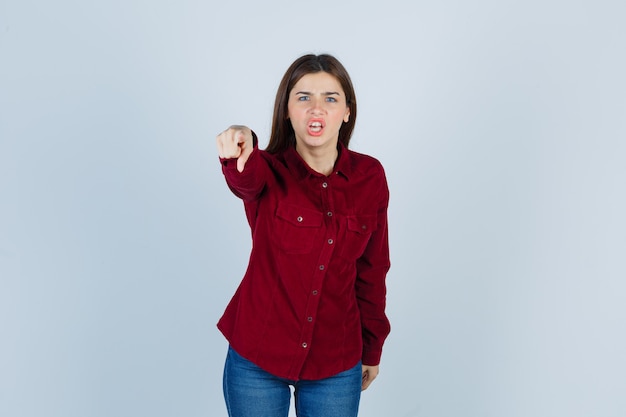 niña apuntando hacia adelante con camisa casual y mirando enojada