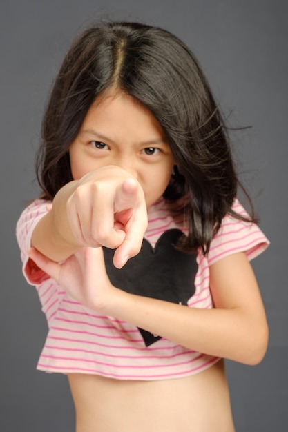 Foto una niña apuntando a la cámara con un corazón en la camisa.