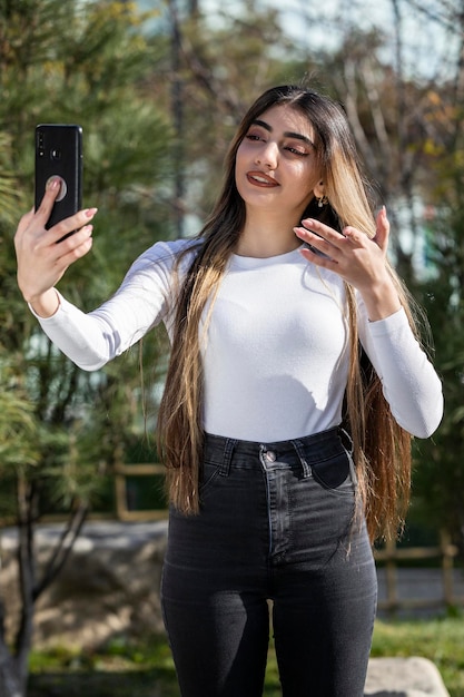 Niña apuntando su mano a su teléfono Foto al aire libre de una joven Foto de alta calidad