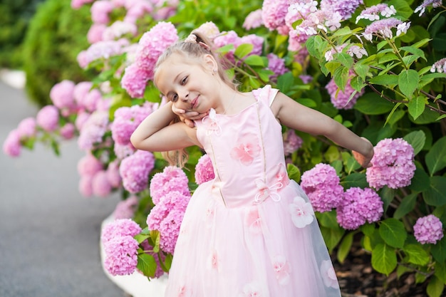 Niña en arbustos de flores de hortensias.