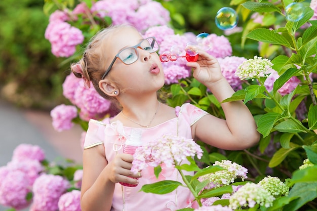 Niña en arbustos de flores de hortensias.