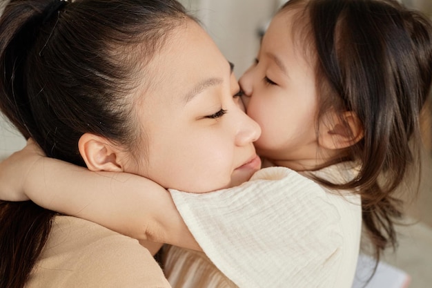 Niña asiática abrazando y besando a su mamá