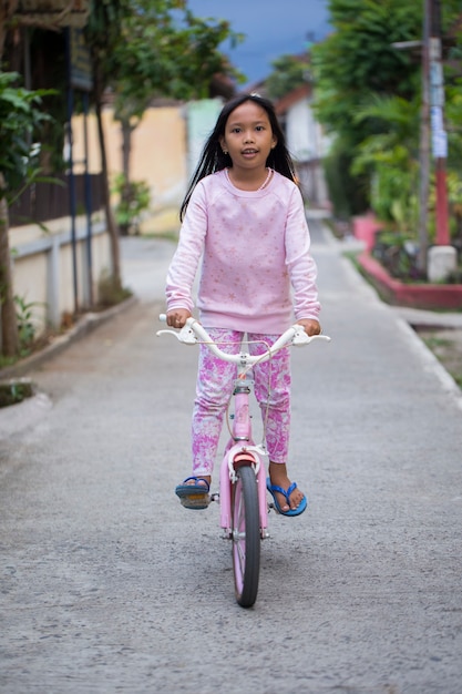 Niña asiática alegre feliz en bicicleta