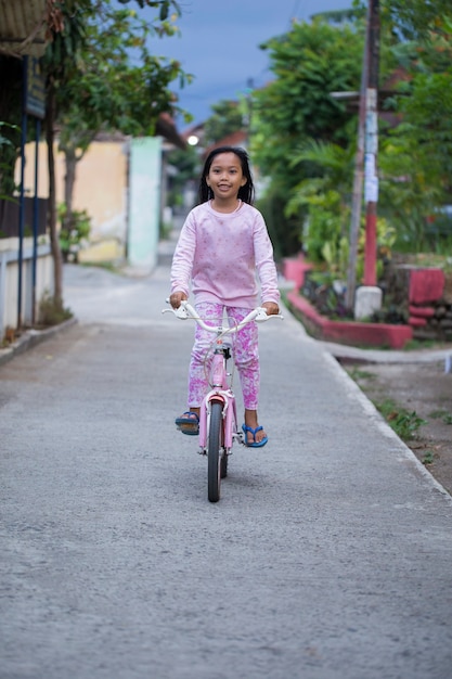 Niña asiática alegre feliz en bicicleta