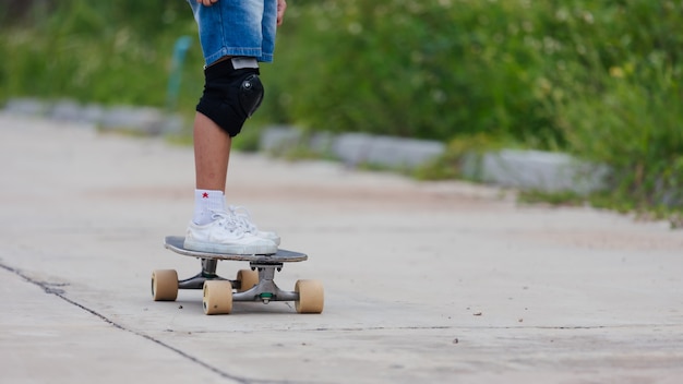 Niña asiática aprendiendo a andar en patineta al aire libre. Niño divirtiéndose y jugando patineta en la carretera durante el día. Actividad infantil y concepto de deporte extremo.