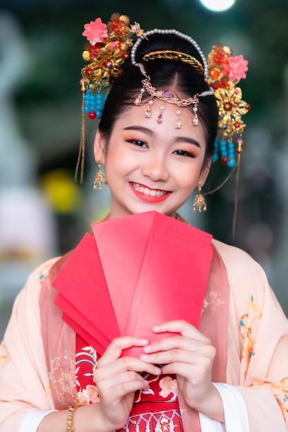 Niña asiática de belleza feliz con trajes antiguos chinos con decoración de sobres rojos para el festival de año nuevo chino celebra la cultura de China en el santuario chino Lugares públicos en Tailandia