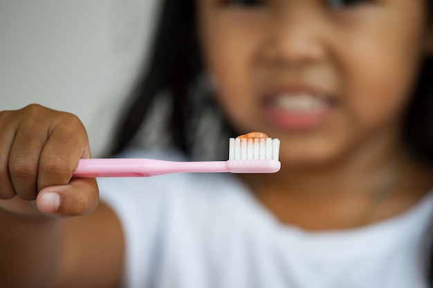 Niña asiática cepillándose los dientes. De cerca