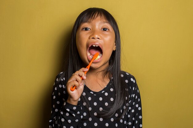 Niña asiática cepillarse los dientes