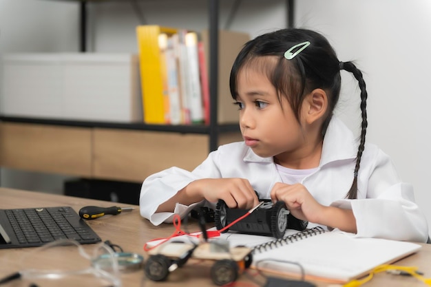 Niña asiática construyendo y codificando robot en STEM classFixing and repair mecánico toy car