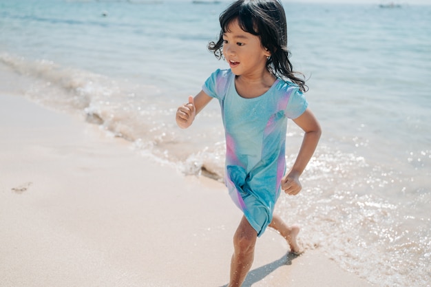 Niña asiática corriendo para evitar las olas