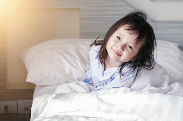 Niña asiática se despierta de su sueño. Buenos días en casa