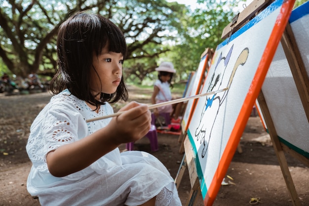 Niña asiática dibujo en el jardín