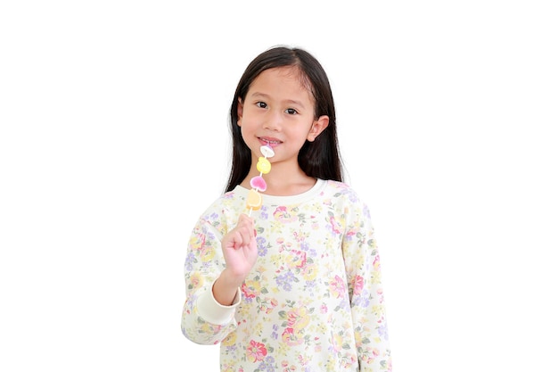 Niña asiática disfruta comiendo caramelos de gelatina aislado sobre fondo blanco.