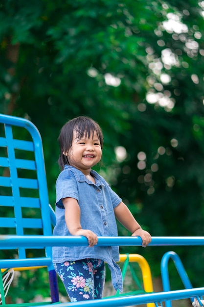 Niña asiática disfruta jugando en un patio de niños