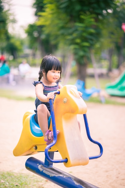 Niña asiática disfruta jugando en un patio de niños