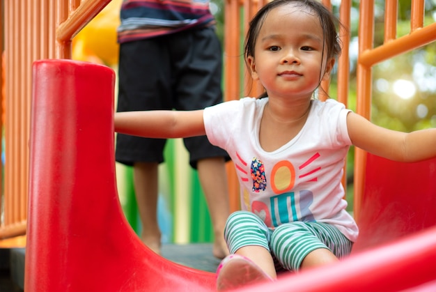 Una niña asiática se disfruta en un parque infantil en una escuela.