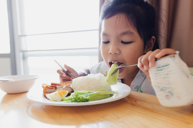 Niña asiática enferma que come alimentos saludables para el almuerzo sola mientras permanece en habitaciones privadas de pacientes en el hospital. Concepto de salud y estilo de vida.