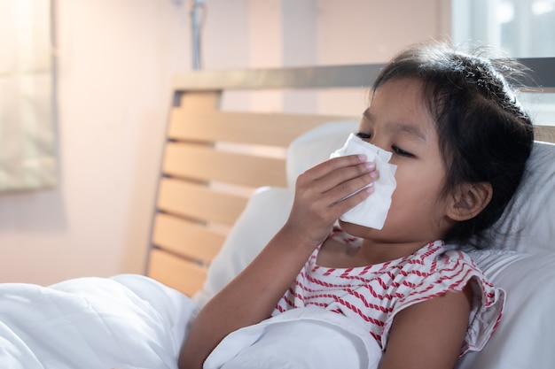 Niña asiática se enferma, tose y estornuda.