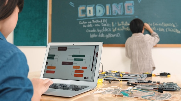 Niña asiática escribiendo instrucciones de ingeniería usando software de IA en la clase de pedagogía