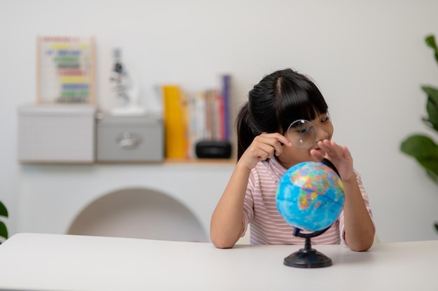 Niña asiática está aprendiendo el concepto de modelo de globo de salvar el mundo y aprender a través de la actividad de juego para la educación de los niños en el hogar