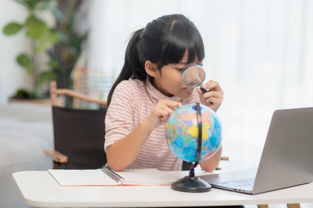 Niña asiática está aprendiendo el concepto de modelo de globo de salvar el mundo y aprender a través de la actividad de juego para la educación de los niños en el hogar