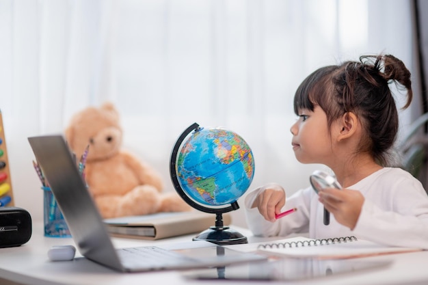 Niña asiática está aprendiendo el concepto de modelo de globo de salvar el mundo y aprender a través de la actividad de juego para la educación de los niños en el hogar