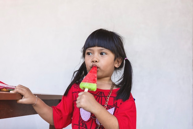 Una niña asiática está comiendo felizmente helado.