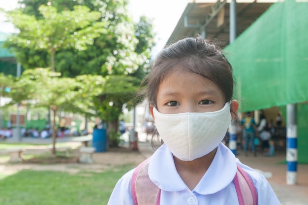 Niña asiática estudiante con mascarilla ir a la escuela