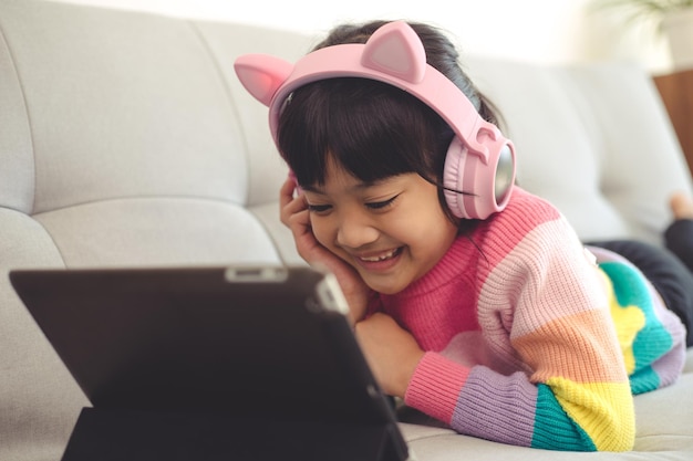 Una niña asiática feliz escuchando música en la sala de estar