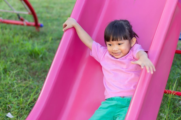 Foto niña asiática feliz sonriendo y riendo ella jugando con un juguete de barra deslizante en el patio de recreo