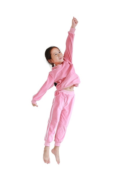 Niña asiática feliz y sonriente en chándal rosa o tela deportiva saltando en el aire aislado sobre fondo blanco.