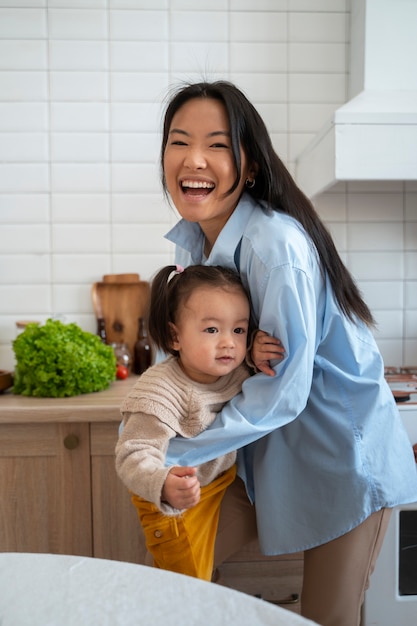 Foto niña asiática gastando en casa en la cocina con su madre