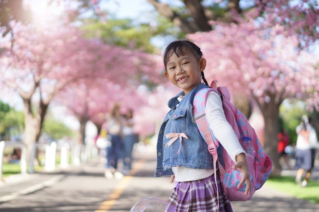 Niña asiática en el jardín bajo el árbol de sakura en flor