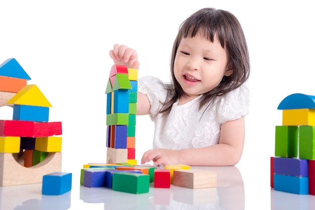 Niña asiática jugando bloque de madera sobre fondo blanco