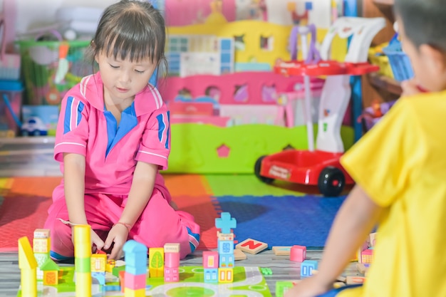 Niña asiática jugando en el espacio juguetes para niños se desarrollan en preescolar, también conocida como guardería