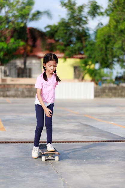 Niña asiática jugando patineta