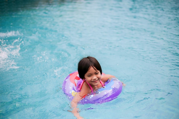 Niña asiática jugando en la piscina