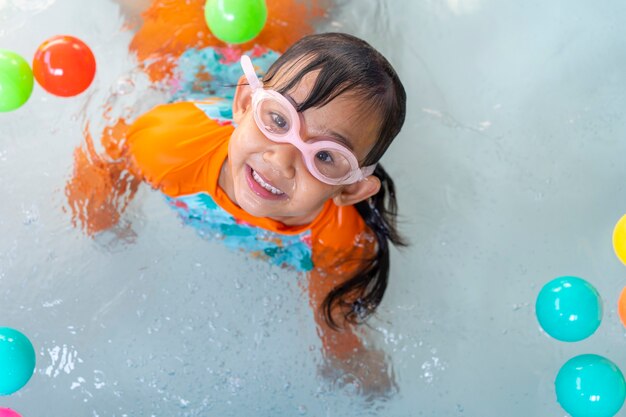 Niña asiática jugando en una piscina