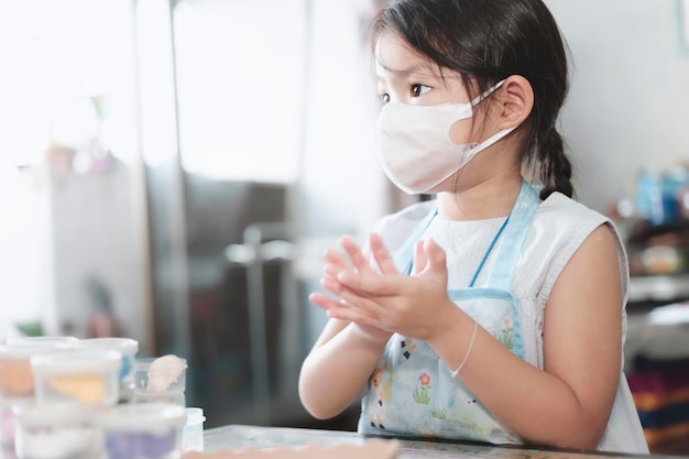 Niña asiática jugando con plastilina en casa