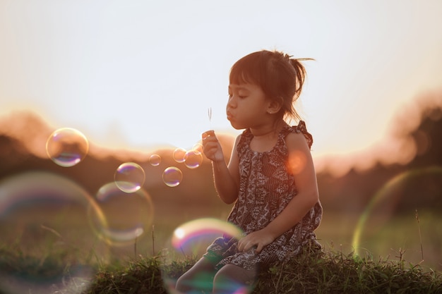 Niña asiática jugando con pompas de jabón